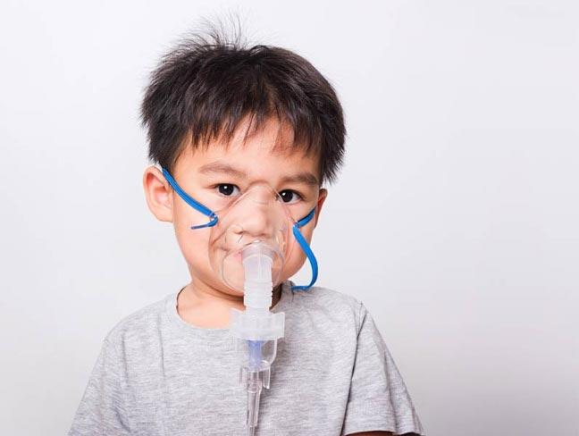 Young child with a nebulizer mask on his face doing treatment.