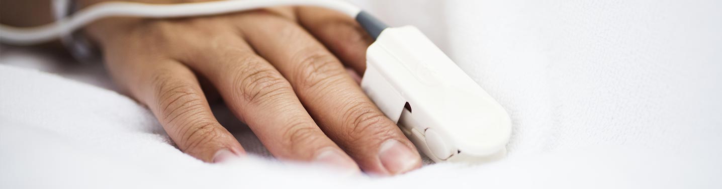 Oximeter on persons finger in bed