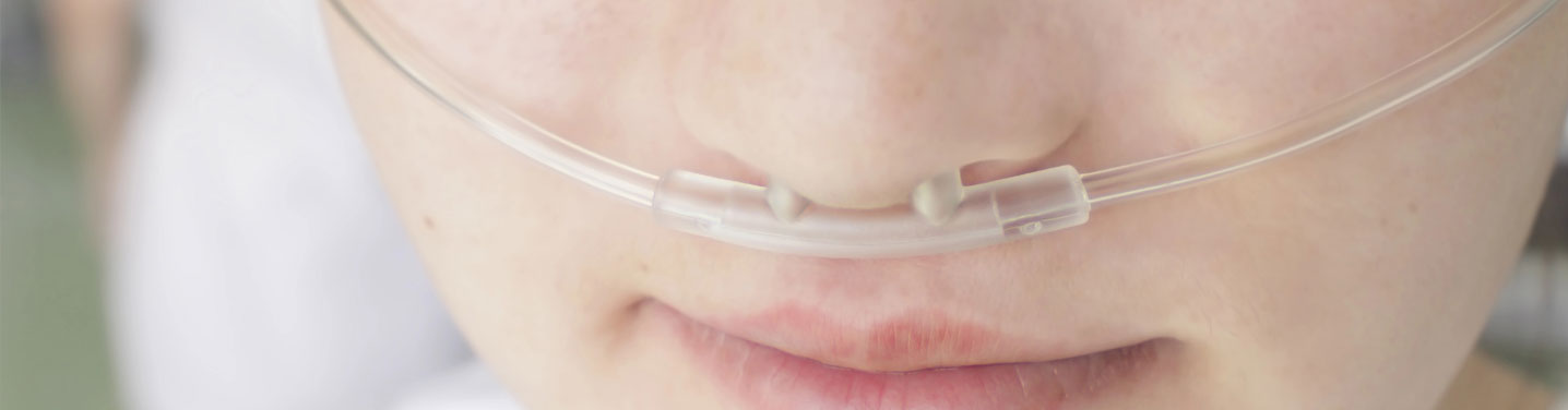 Closeup of a young girl receiving oxygen through small tube.