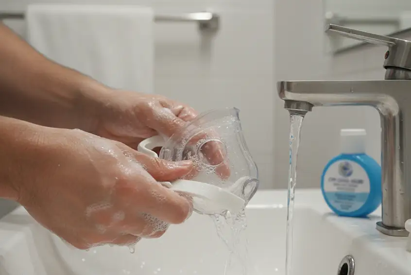 Man washing his CPAP mask in the sink with soap and water